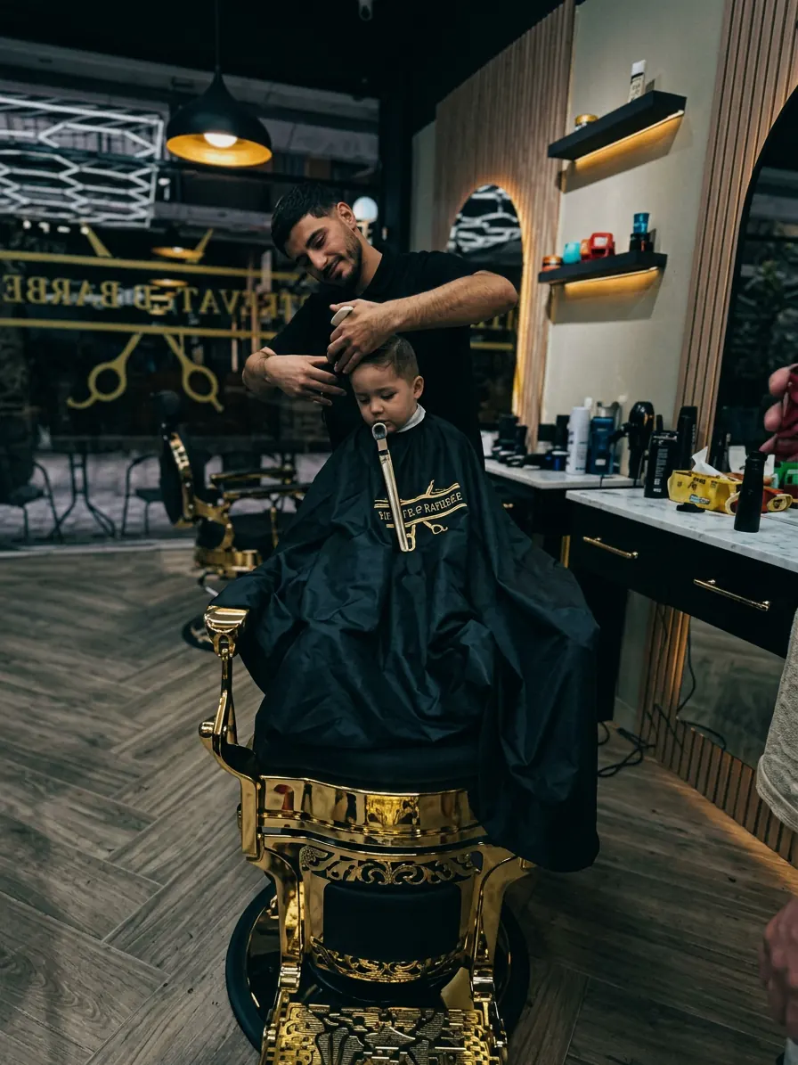 A barber cutting a young client’s hair in a gold barber chair